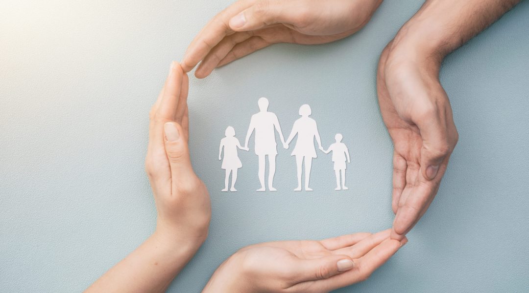 Hands with cut out paper silhouette on table. Family care concept.