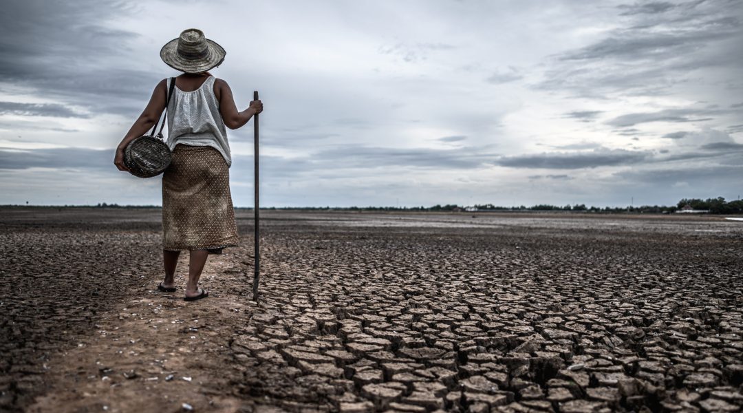 Women standing on dry soil and fishing gear, global warming and water crisis